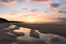 Sunrise reflected in tidal sand pools at St Clair Beach, Dunedin, New Zealand. 