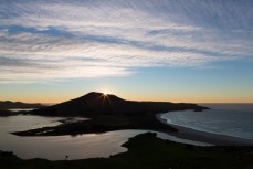 The sun peeks over the highest point (400m) on the Cape Saunders land mass on Otago Peninsula, Dunedin, New Zealand. 