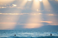 Light beams shine down on two surfers at Blackhead Beach, Dunedin, New Zealand. 