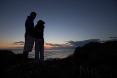Michael Meier (left) and Eva Klein, both of Austria, watch the sun set after an evening surf at Blackhead Beach, Dunedin, New Zealand. 