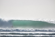 A surfer rides a clean, hollow waves at a secluded bay in the Catlins, Otago, New Zealand. 