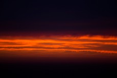 Blood red sunrise sandwiched between dark clouds and the horizon over St Clair Beach, Dunedin, New Zealand. 