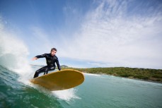 Local surfboard shaper Skep rides a longboard at Blackhead Beach, Dunedin, New Zealand. 