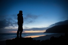 Vic Sturt watches the sunset at a remote beach on Otago Peninsula, Dunedin, New Zealand. 
