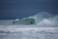 A surfer races a section beneath stormy skies at Aramoana, Dunedin, New Zealand. 
