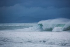 A wave breaks beneath stormy skies at Aramoana, Dunedin, New Zealand. 