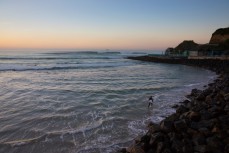 Local artist Jason Low walks out for a dawn surf at St Clair Beach, Dunedin, New Zealand. 