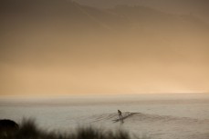 A surfer rides a wave on the Kaikoura coast, Kaikoura, New Zealand. 