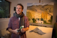 Justin Summerton at home in his studio with a freshly finished painting of the Cardrona Hotel, St Clair, Dunedin, New Zealand. 