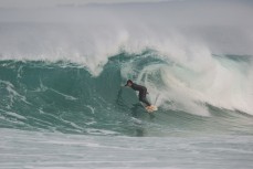 A surfer rides a hollow wave at Blackhead Beach, Dunedin, New Zealand.