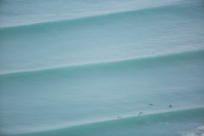 Surfers paddle into position for a set at Aramoana, Dunedin, New Zealand. 