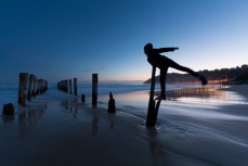 Taya stands on a pole to avoid getitng wet shoes at St Clair Beach, Dunedin, New Zealand. 