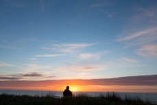 Andy Sutherland watches the sunrise on the beach at Okitu, Gisborne, Eastland, New Zealand. 