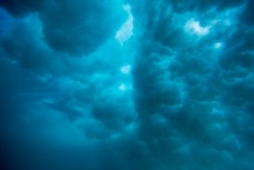 A wave billows clouds of turbulence as a surfer slips beneath it at Blackhead Beach, Dunedin, New Zealand. 