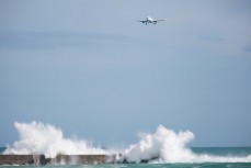 An Air New Zealand plane flies over as swell crashes into a breakwall at Lyall Bay, Wellington, New Zealand. 