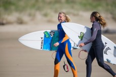 Young surfer girl grommets head out for a wave at Makarori Beach, Gisborne, Eastland, New Zealand. 
