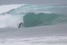 A surfer rides a glassy peak at Aramoana Beach, Dunedin, New Zealand. 