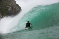 Freestyle skier and photographer Nick Rapley in a hollow wave at a remote beach in the Catlins, Southland, New Zealand. 