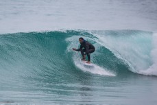 A surfer rides a wave at Blackhead Beach, Dunedin, New Zealand. 