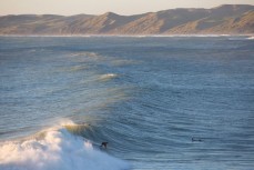 A surfer rides a warping wall into the bay at Raglan, Waikato, New Zealand. 