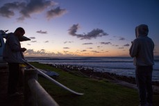 Surfers watch the sun set at Raglan, Waikato, New Zealand. 