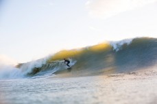 A surfer lines up the ledge in a rising swell at Manu Bay, Raglan, New Zealand. 