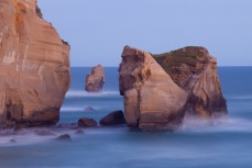 The South Pacific Ocean meets the cliffs at Tunnel Beach on dusk, Dunedin, New Zealand. 