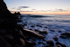 Waves peeling along a remote boulder beach, Norfolk Island, South Pacific Ocean.