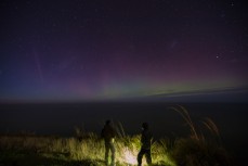 Onlookers watch the Aurora Australis in the southern sky from St Clair, Dunedin, New Zealand. 