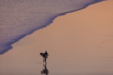 A surfer runs to the beach after a dusk session at Blackhead Beach, Dunedin, New Zealand. 