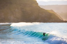 A surfer unleashes in fun afternoon waves at Whareakeake, Dunedin, New Zealand. 