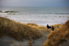 Two girls head out for a surf in fun waves at Aramoana, Dunedin, New Zealand. 