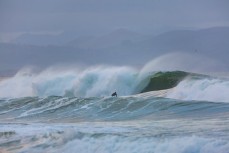 A surfer stands at the bottom of a decent set wave at Aramoana, Dunedin, New Zealand. 