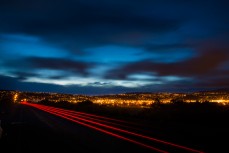 Car lights stream by after a quality session at St Kilda Beach, Dunedin, New Zealand. 
