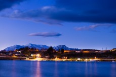 Car lights stream around houses on the western shore of Lake Wanaka, New Zealand. 