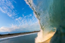 Sunset illuminates a breaking wave at St Kilda Beach, Dunedin, New Zealand. 