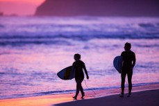 Surfers emerge from the water on dark at St Kilda Beach, Dunedin, New Zealand. 