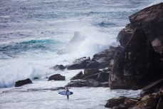 A surfer prepares to negotiate jump rock at LA  on the Northern beaches of Sydney, NSW, Australia. 