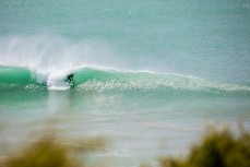 A surfer rides a tube at a remote beachbreak in the Catlins, New Zealand. 