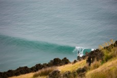 A surfer rides a wave at a beach on the North Coast of Dunedin, New Zealand. 