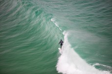 A surfer rides a wave at a beach on the North Coast of Dunedin, New Zealand. 