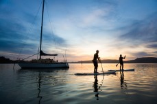 Craig Latta and Di Brenssell ride stand-up paddleboards at Deborah Bay on the Otago Harbour at Port Chalmers, Dunedin, New Zealand. 