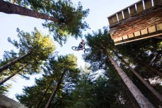 A rider spins off the log during the Crankworx World Tour slopestyle event held at Skyline Rotorua, Rotorua, New Zealand, March 9-13, 2016.