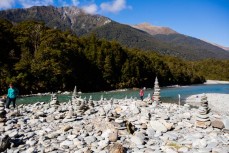 Rock cairns and tourists enjoy a clear crisp autumn day at Blue Pools near Makarora, Wanaka, New Zealand. 