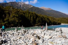 Rock cairns and tourists enjoy a clear crisp autumn day at Blue Pools near Makarora, Wanaka, New Zealand. 