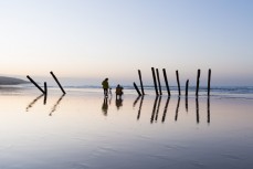 Tourists line up to photograph the remnants of the poles on St Clair Beach, Dunedin, New Zealand. 