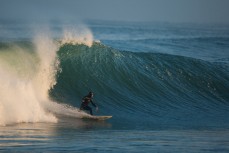 A surfer bottom turns on a solid wave at Blackhead Beach, Dunedin, New Zealand. 
