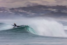A surfer pokes through a wave in fun conditions at Blackhead Beach, Dunedin, New Zealand. 