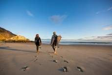 Surfers Zen and Christina head out for a surf at a beach near, Dunedin, New Zealand. 