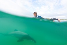 Taya Morrison surfing with Hector's Dolphins at Curio Bay in the Catlins, Southland, New Zealand. 